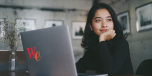 女性がパソコンの前で遠くを見ている