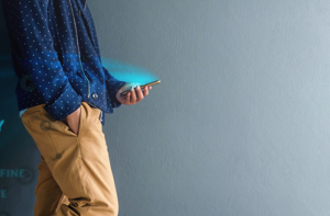 Person looking at their phone learning Japanese through unique student portal with a blue shirt and gray background